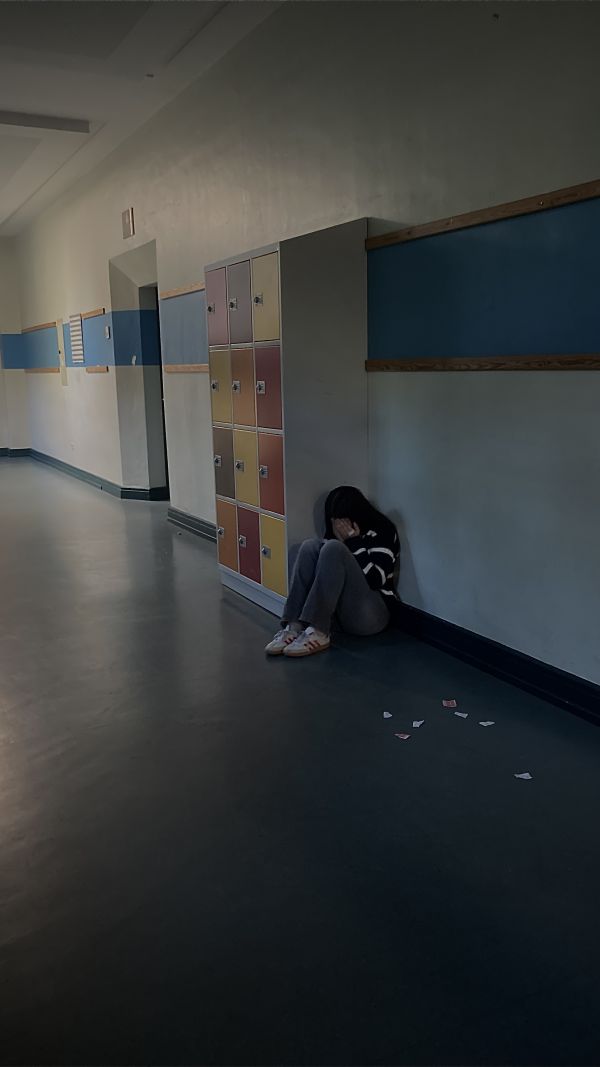 Die Schülerin sitzt alleine im Schulgang und weint.