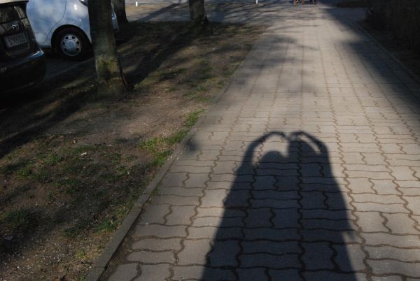 Özlem und Güler umarmen sich und formen zusammen ein Herz über ihren Köpfen und fotografieren ihren Schattenwurf.