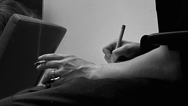 smoking, concentrated and thoughtful mood, drawing and writing in a sketchbook