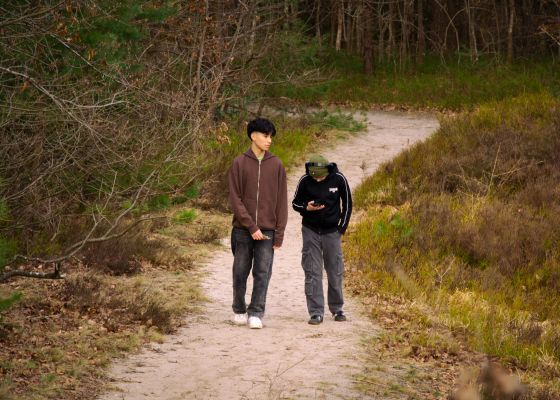 Nelson und Kian gehen spazieren. Nelson genießt die Natur, während Kian nur Augen für sein Handy und die digitale Welt, die sich dahinter verbirgt, hat.